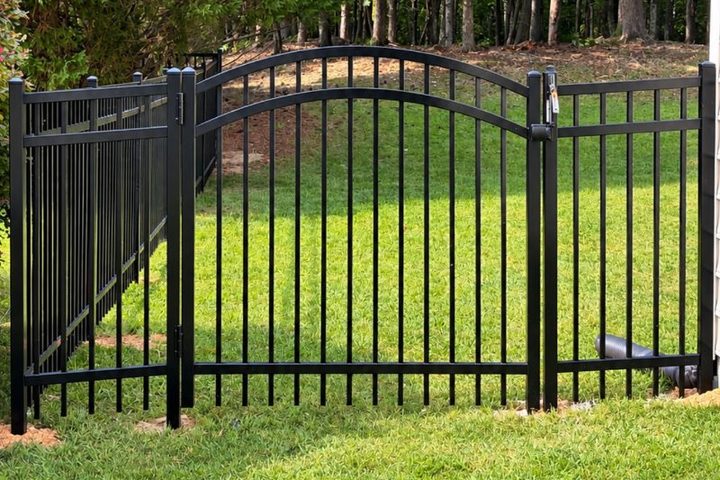 Arched aluminum gate set into a black ornamental fence