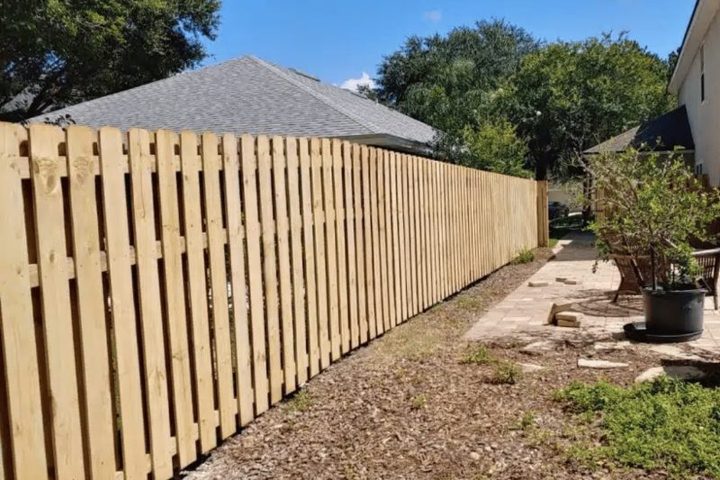Shadowbox wood fence beside a mulched garden bed and walkway