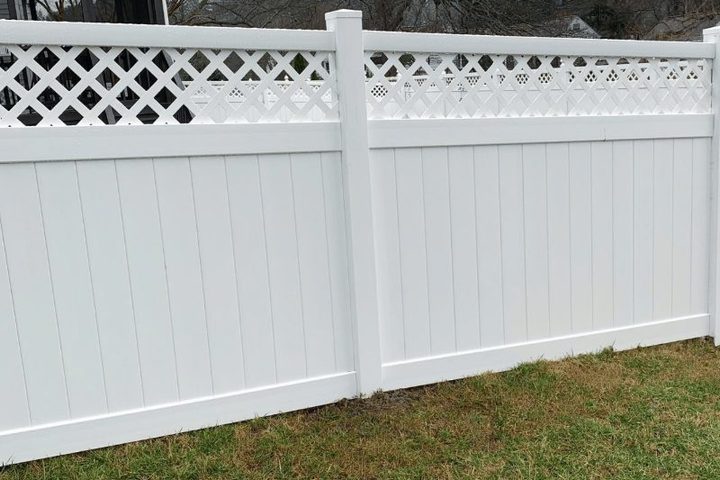 White vinyl privacy fence with a lattice top along a lawn