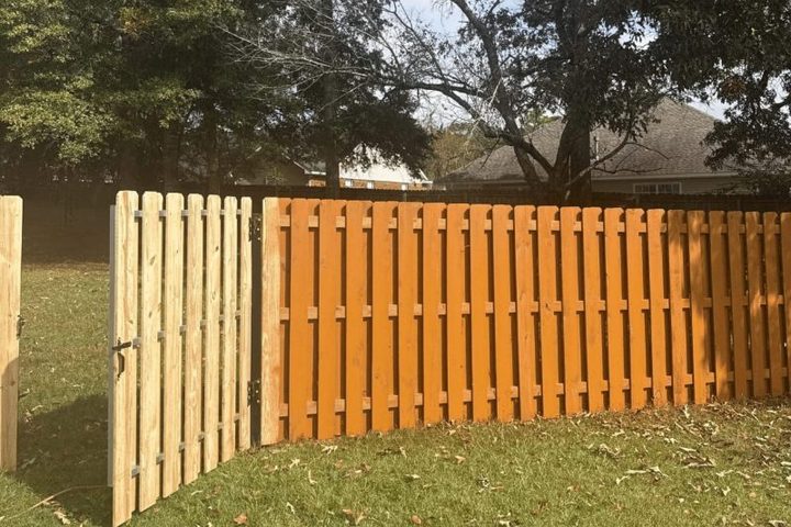 Stained wood gate standing open in a fenced back yard