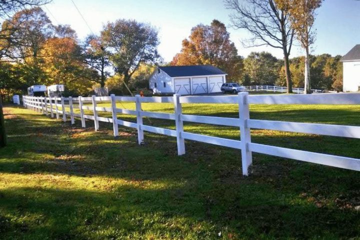 White ranch-rail fence running across an open front lot